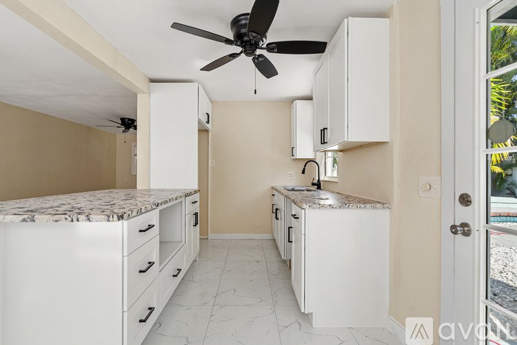 A kitchen with a marble countertop and white cabinets.