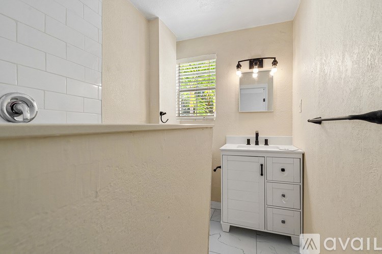 A bathroom with a white cabinet and a window with blinds.