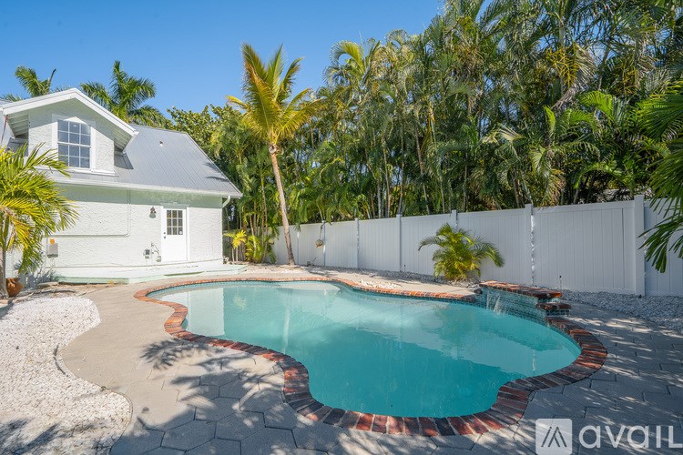 A house with a pool surrounded by a white fence and palm trees.