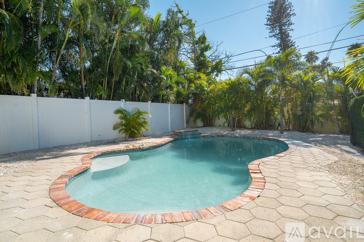 A small pool surrounded by a white fence and trees.