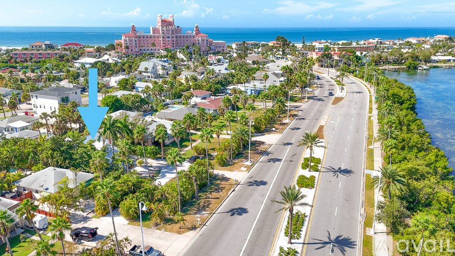 A street view of a residential area with a large house and a road running through it.