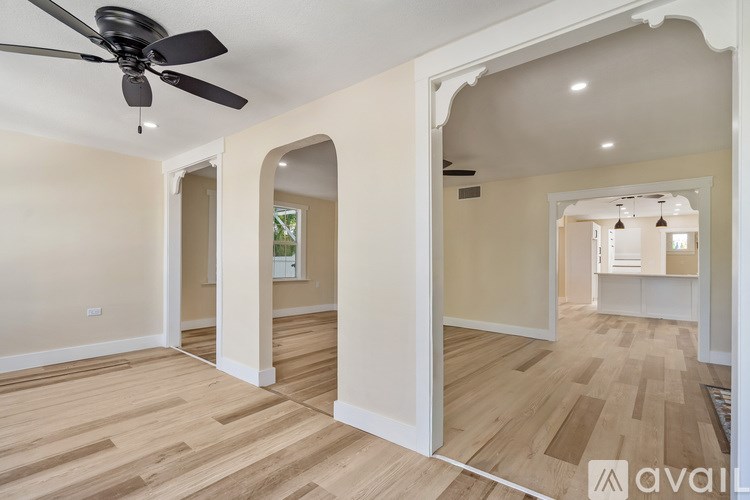 A spacious room with a ceiling fan and wooden flooring.