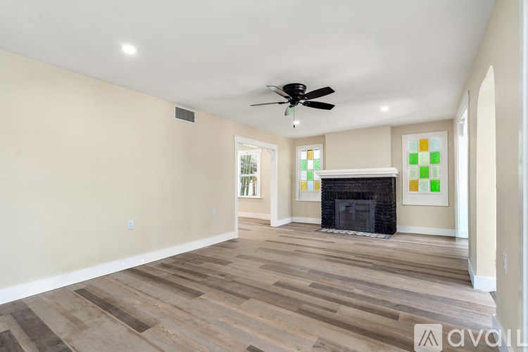 A spacious living room with a fireplace and a fan on the ceiling.