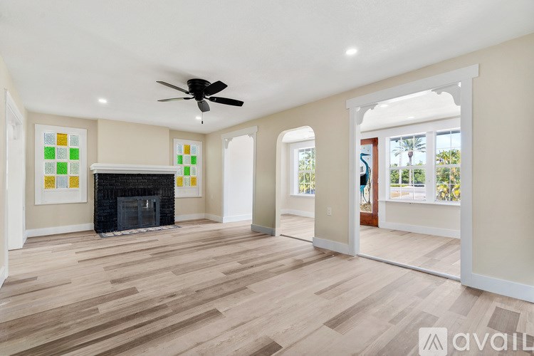 A spacious living room with a fireplace and a ceiling fan.