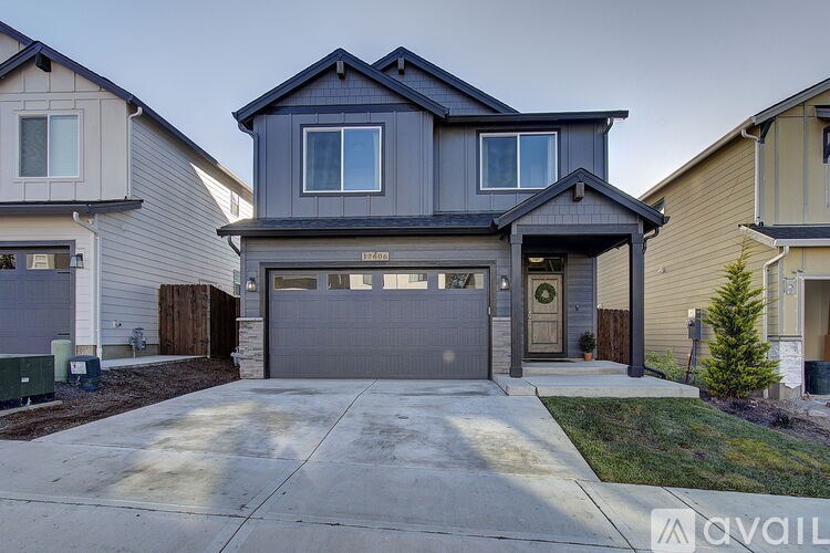 A modern house with a grey front yard and a black garage door.