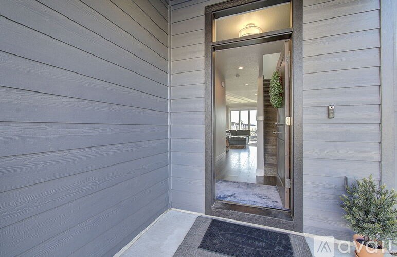 A modern house entrance with a glass door and a black mat on the floor.