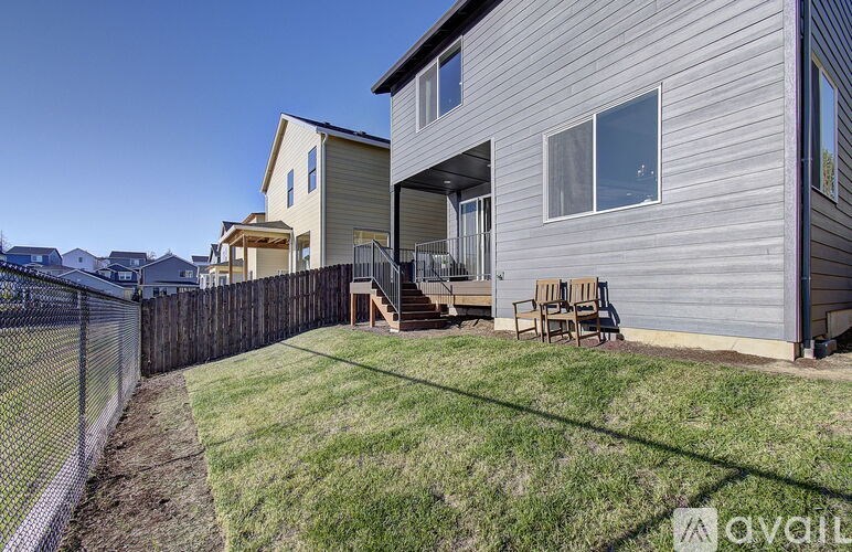 A house with a grey siding and a fence in front of it.