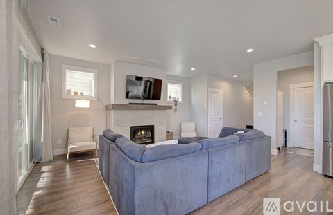 A modern living room with a grey couch and a fireplace.