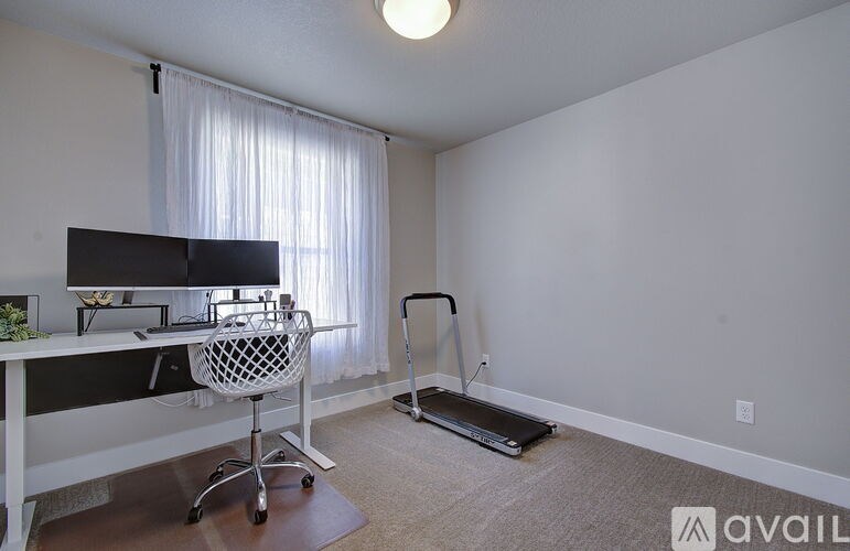 A room with a desk, chair, and a treadmill.