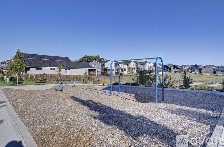 A playground with a blue swing set and a gravel ground.