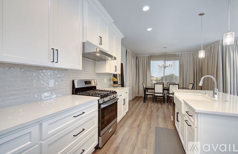 A modern kitchen with white cabinets and a wooden floor.
