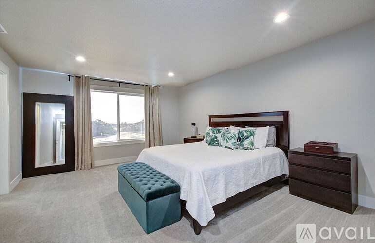 A bedroom with a large bed and a window with curtains.