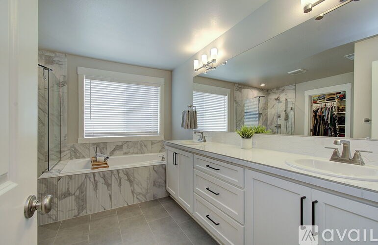A bathroom with a marble tub surround and a large mirror.
