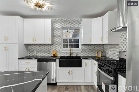 A modern kitchen with white cabinets and black countertops.