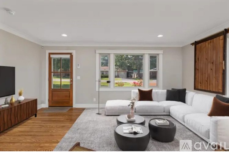 A living room with a white couch, a grey rug, and a wooden floor.