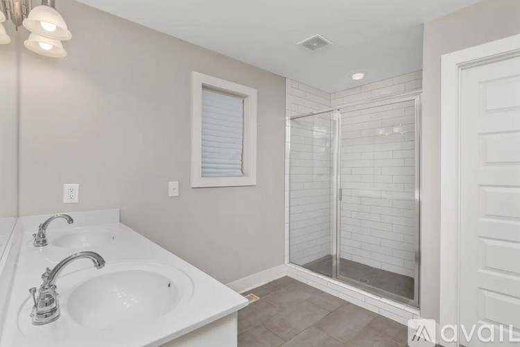A white sink with two faucets is on a white countertop in a bathroom.
