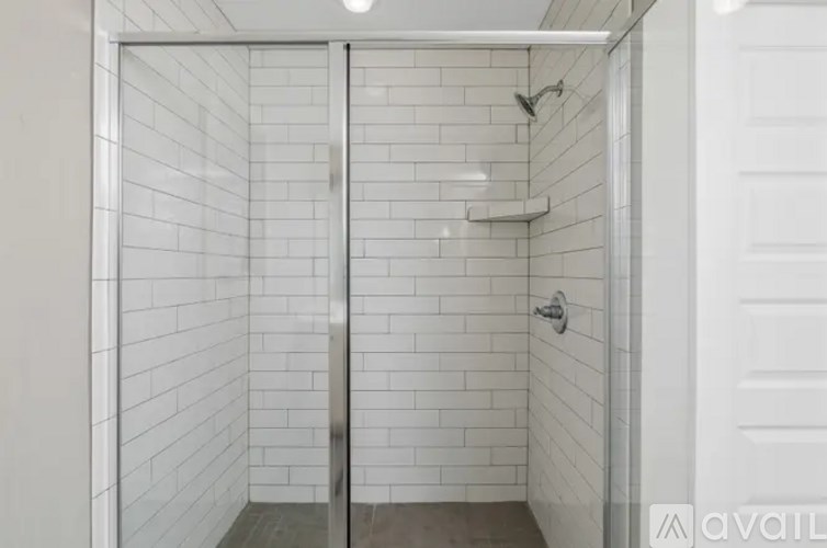 A white tiled bathroom with a glass door.