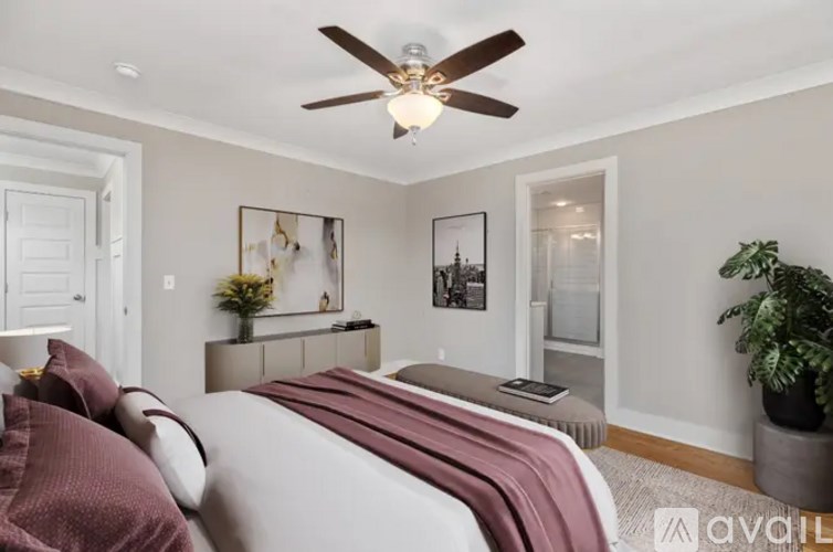A bedroom with a bed, a ceiling fan, and a plant.