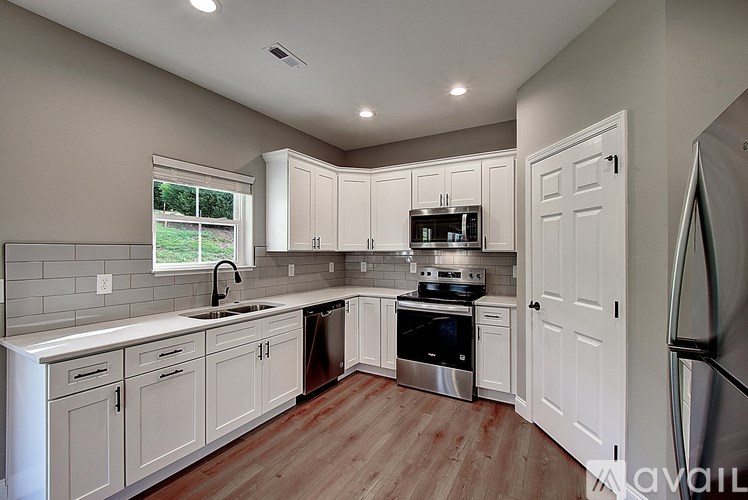A kitchen with white cabinets and a stainless steel refrigerator.