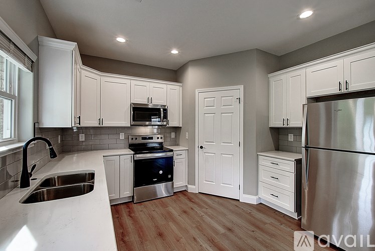 A kitchen with white cabinets and a stainless steel refrigerator.