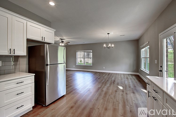 A kitchen with white cabinets and a wooden floor.