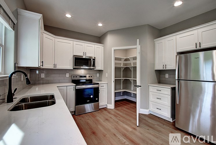A kitchen with white cabinets and a stainless steel refrigerator.