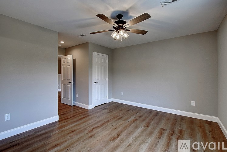 A room with a ceiling fan and wooden flooring.
