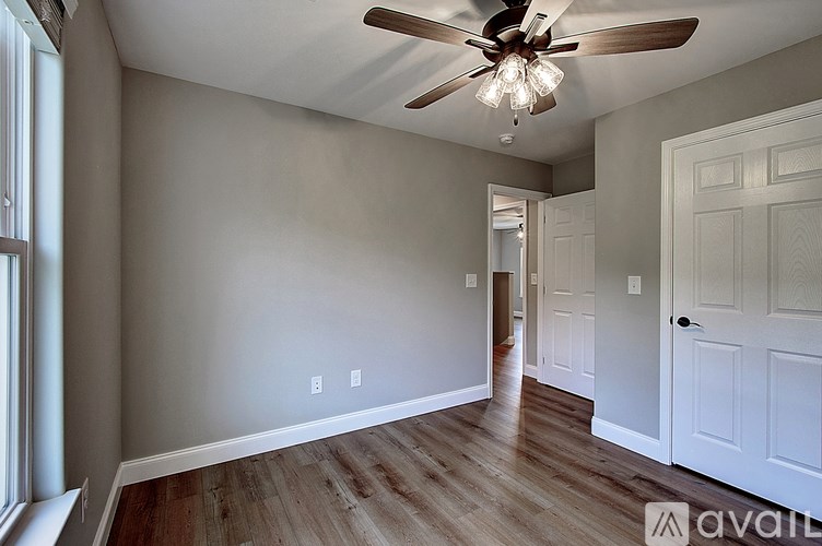 A room with a ceiling fan and wooden flooring.