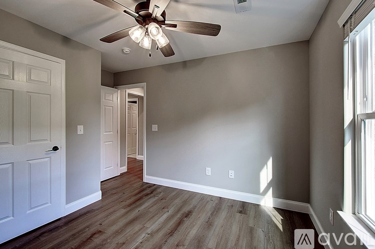 A room with a ceiling fan and wooden flooring.