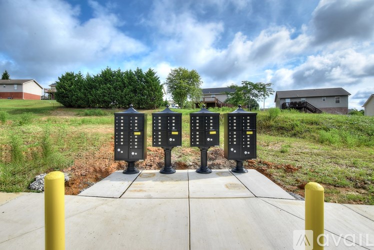 Four black electronic boxes are on a concrete slab with yellow posts on the side.