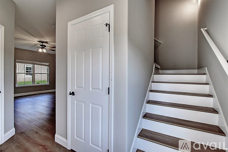 A white door is in a hallway with a staircase.