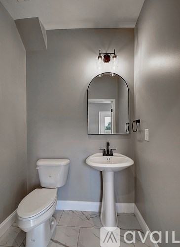 A bathroom with a toilet, pedestal sink and mirror.