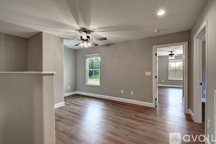 A spacious room with wooden flooring and a ceiling fan.