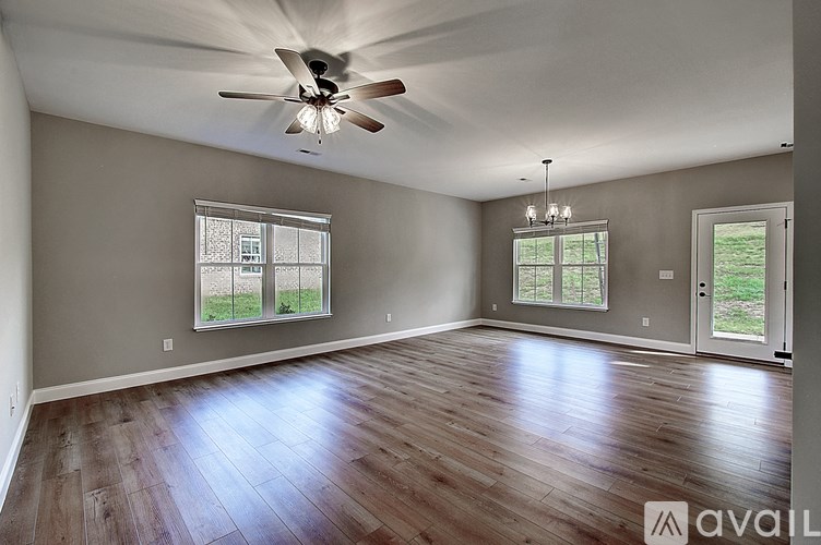 A spacious room with a ceiling fan and hardwood flooring.