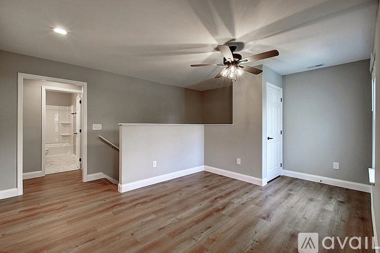 A room with a ceiling fan and wooden flooring.