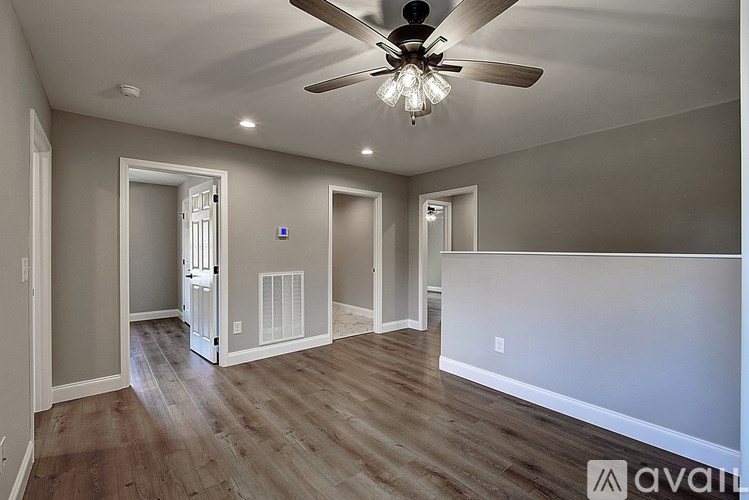 A spacious room with a ceiling fan and wooden flooring.