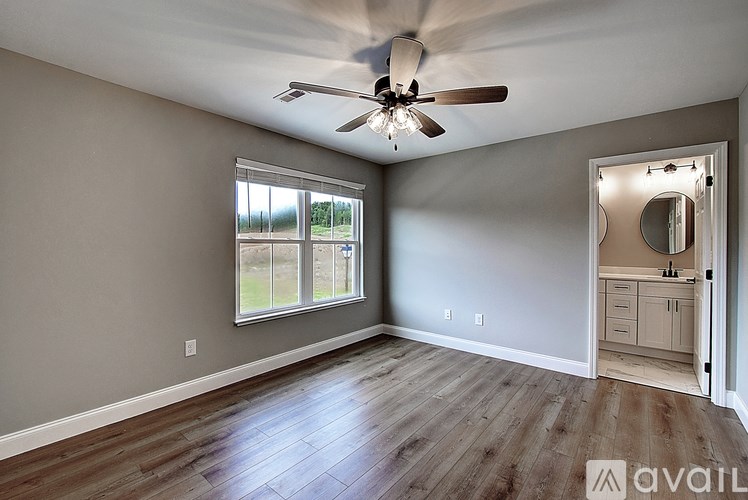 A room with a ceiling fan and a large window.