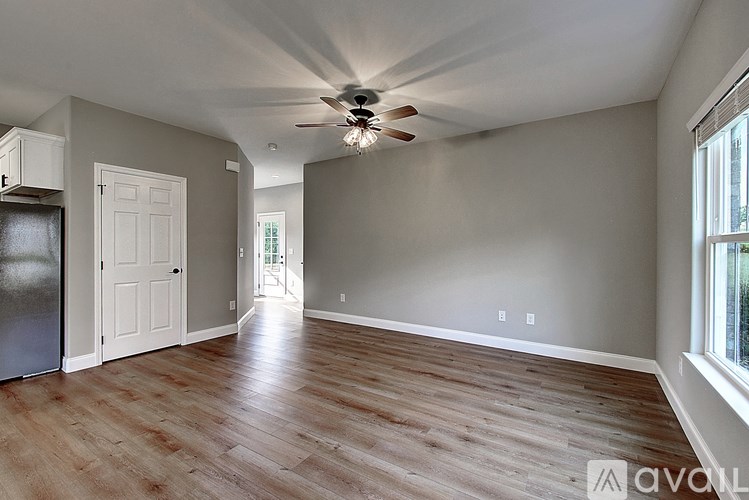 A spacious room with a ceiling fan and wooden flooring.
