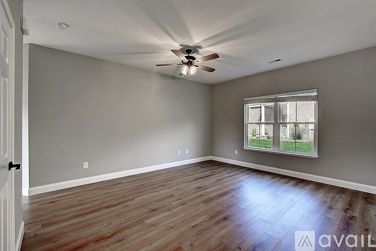 A room with a ceiling fan and a window showing a view of trees.