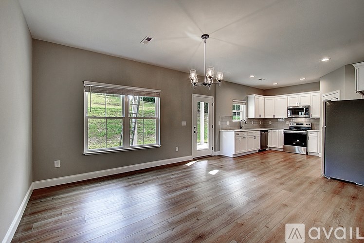 A spacious kitchen and living room with wood flooring and a large window.