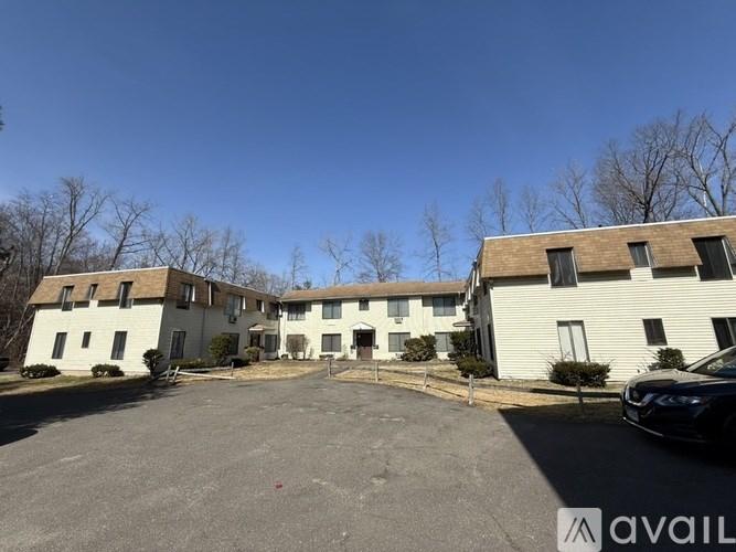 A parking lot in front of a white building with a black car parked in the lot.