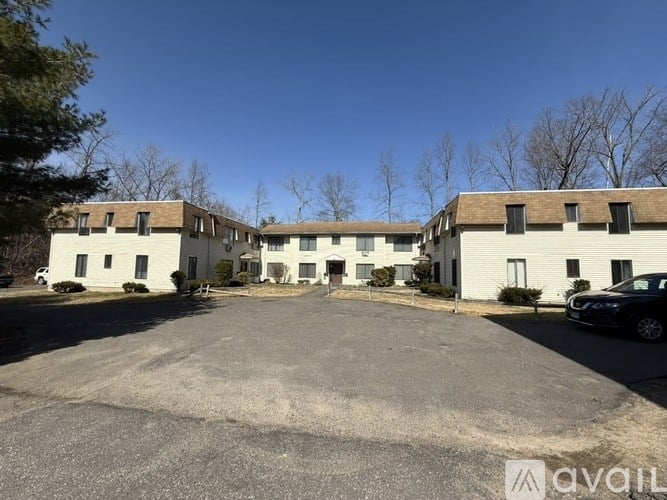 A parking lot with a building in the background and a car parked in the lot.