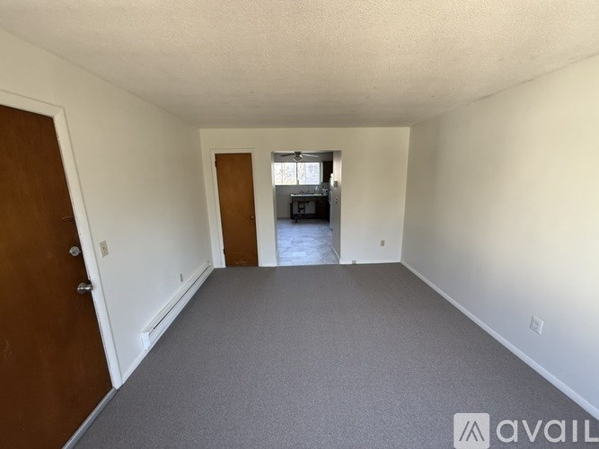A room with a carpeted floor and a door on the left.