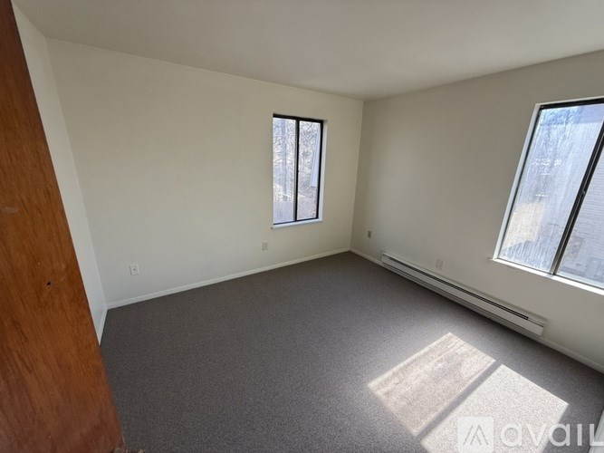 A room with a window and a carpeted floor.