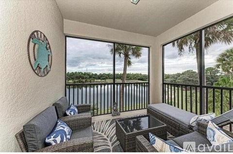 A balcony with a table and chairs overlooking a body of water.