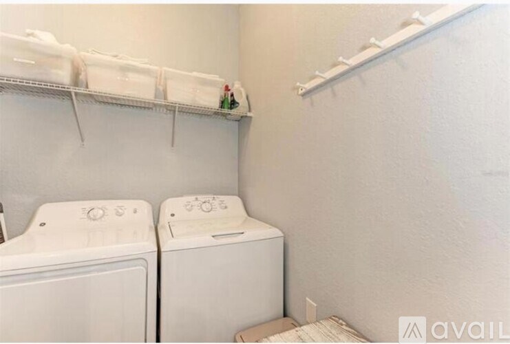A small laundry room with two washing machines and a shelf above them.