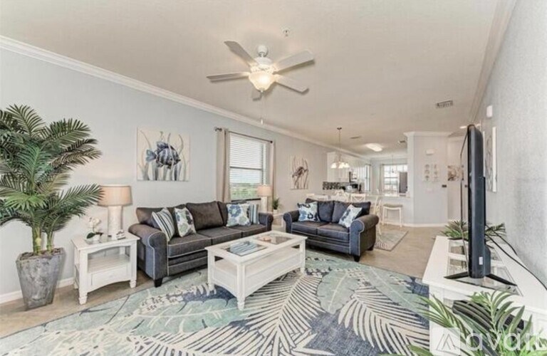 A living room with a couch, a coffee table, a television, and a ceiling fan.