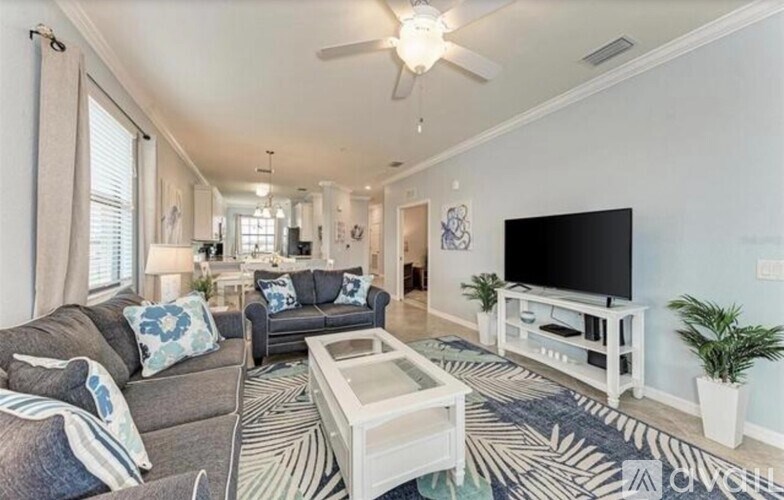 A living room with a grey couch, a white coffee table, and a flat screen TV.
