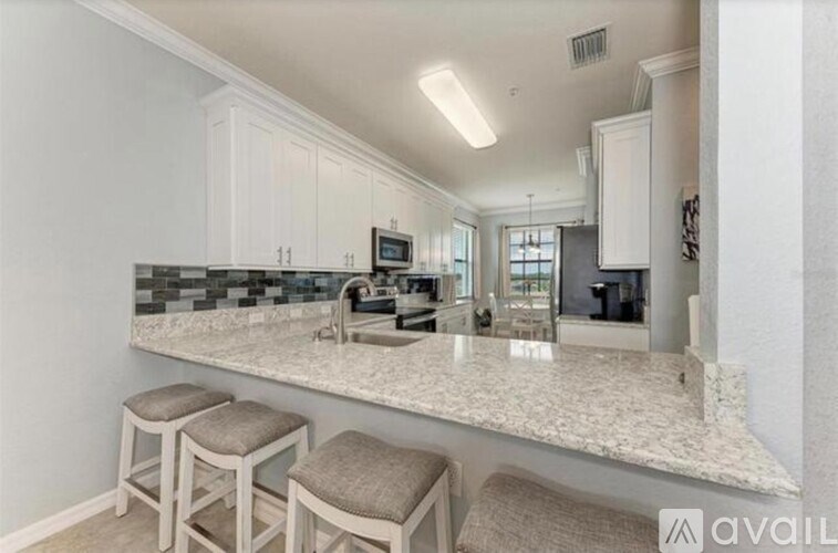 A kitchen with a granite countertop and bar stools.