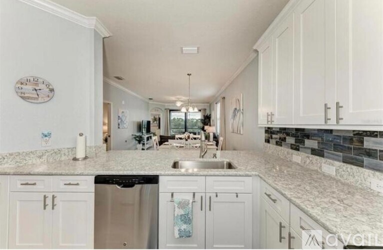 A kitchen with white cabinets and a marble countertop.